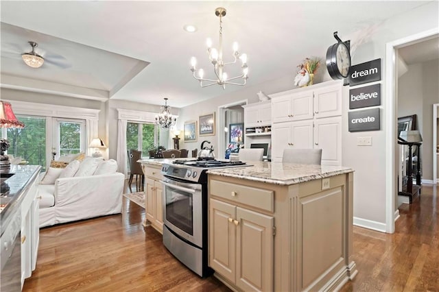 kitchen featuring a notable chandelier, wood finished floors, open floor plan, a center island, and stainless steel gas stove