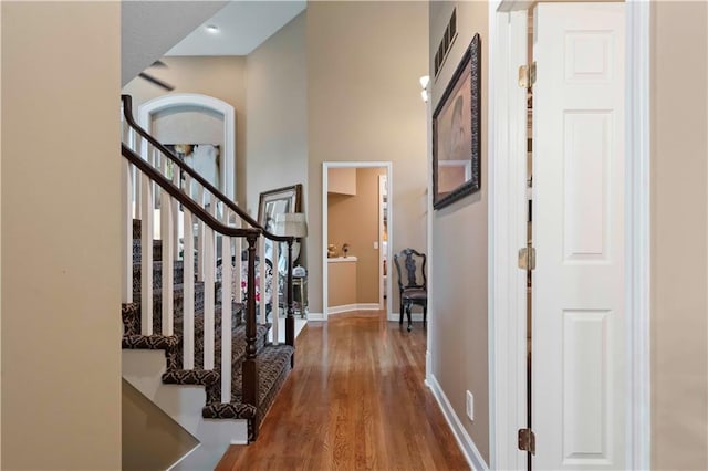 entryway featuring visible vents, baseboards, a towering ceiling, wood finished floors, and stairs