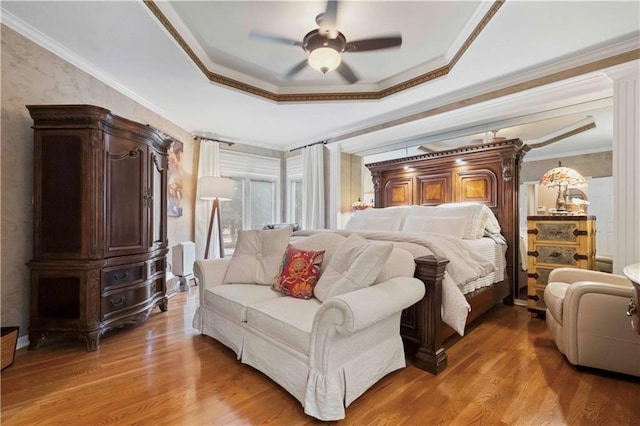 bedroom featuring ornamental molding, a raised ceiling, ceiling fan, and wood finished floors