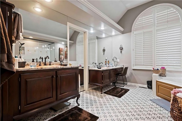 full bathroom featuring two vanities, baseboards, vaulted ceiling, and a sink