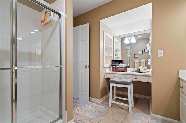 bathroom with tile patterned flooring, a notable chandelier, vanity, baseboards, and a stall shower