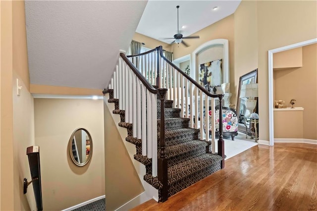 stairs featuring ceiling fan, a textured ceiling, wood finished floors, and baseboards