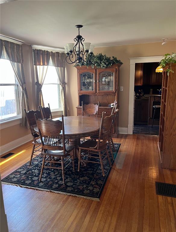 dining space featuring wood-type flooring and a notable chandelier