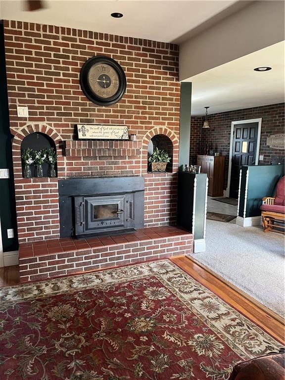 unfurnished living room with hardwood / wood-style flooring and a brick fireplace