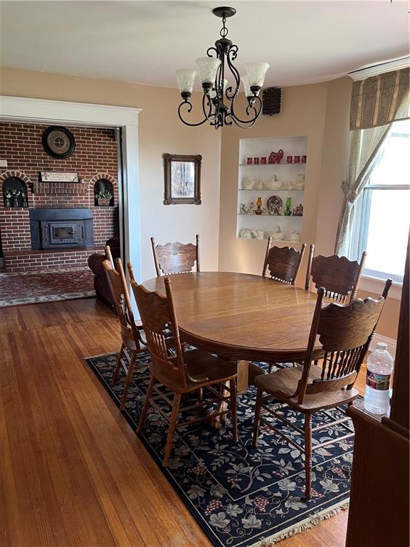 dining space featuring an inviting chandelier, a brick fireplace, and wood-type flooring