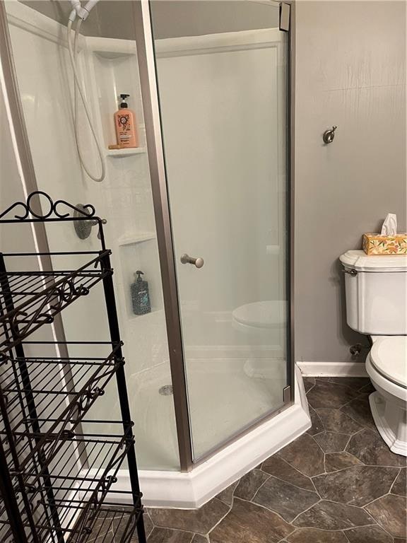 bathroom featuring a shower with shower door, toilet, and tile patterned flooring