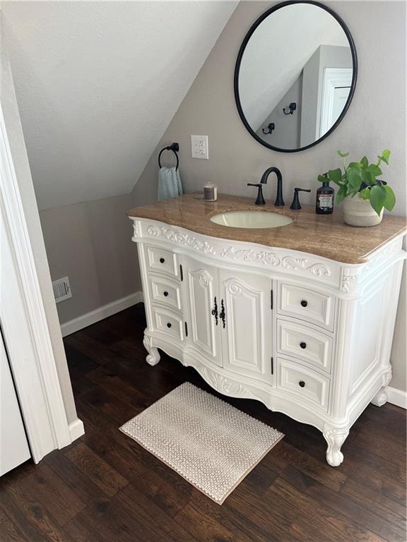 bathroom featuring hardwood / wood-style flooring, vaulted ceiling, and vanity