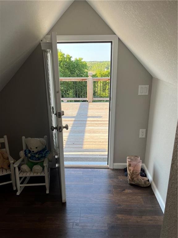 entryway with vaulted ceiling, hardwood / wood-style floors, and a textured ceiling