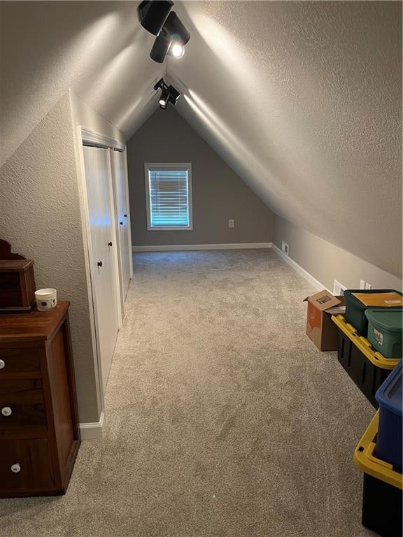 bonus room featuring a textured ceiling, light colored carpet, and vaulted ceiling