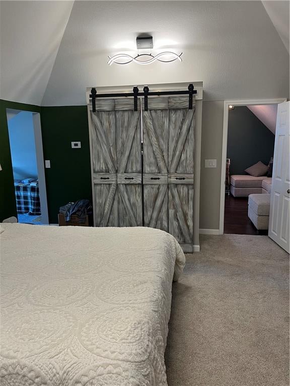 carpeted bedroom featuring vaulted ceiling and a barn door