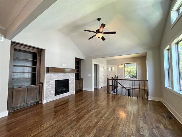 unfurnished living room with a stone fireplace, dark wood-type flooring, ceiling fan, and vaulted ceiling