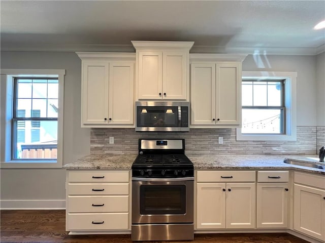 kitchen with appliances with stainless steel finishes, white cabinetry, a wealth of natural light, and dark hardwood / wood-style floors