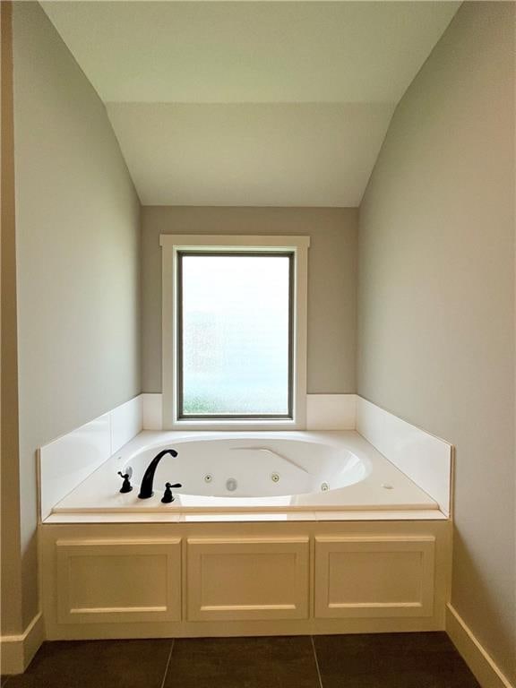 bathroom with tile patterned floors, a bath, and vaulted ceiling