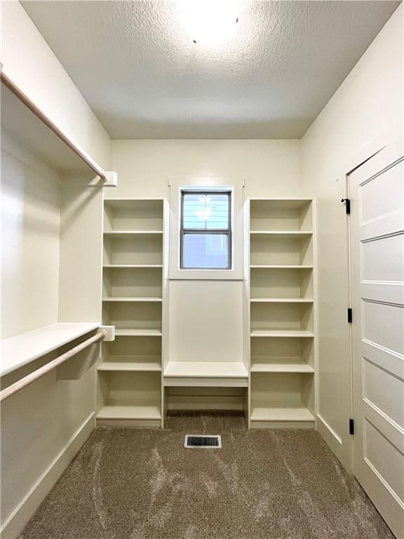 walk in closet featuring dark colored carpet