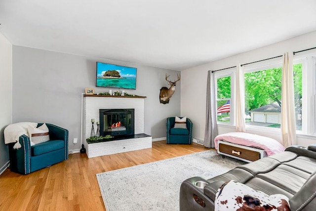 living room featuring light hardwood / wood-style flooring and a brick fireplace