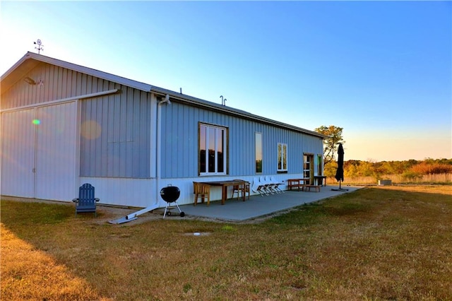 property exterior at dusk featuring a yard and a patio area