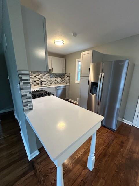 kitchen featuring tasteful backsplash, appliances with stainless steel finishes, dark hardwood / wood-style floors, and gray cabinets