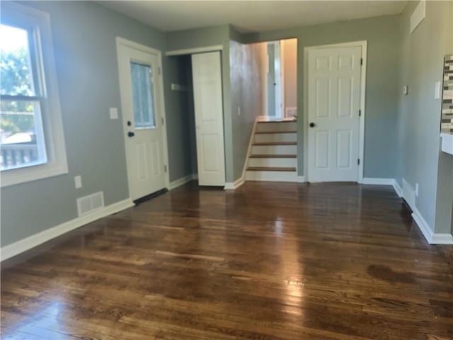 interior space with stairs, visible vents, baseboards, and wood finished floors