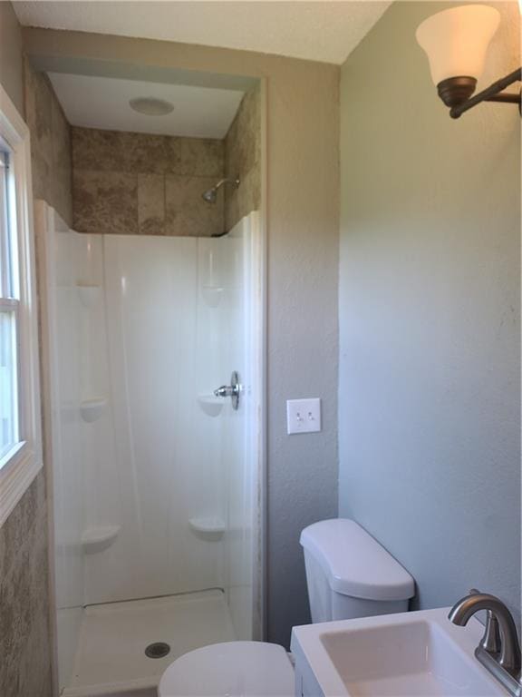 full bathroom with a stall shower, a sink, and toilet