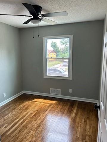 unfurnished room featuring dark wood-style floors, a textured ceiling, visible vents, and baseboards