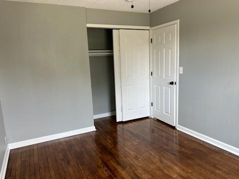 unfurnished bedroom featuring dark hardwood / wood-style flooring and a closet