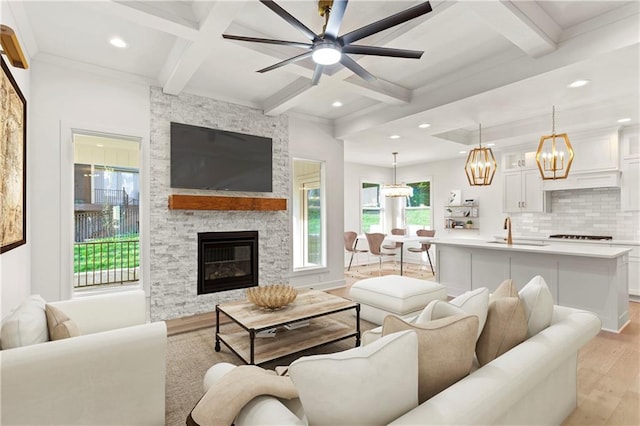 living room with coffered ceiling, sink, light hardwood / wood-style flooring, ceiling fan, and a fireplace