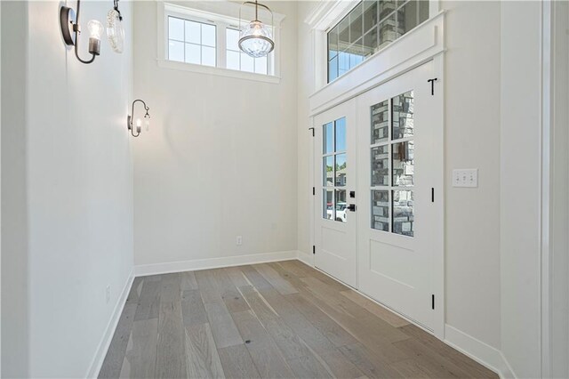 entryway with hardwood / wood-style flooring, a chandelier, french doors, and a healthy amount of sunlight