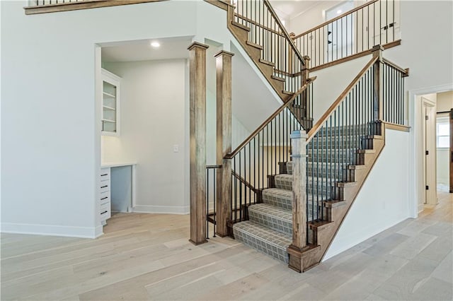 stairs featuring hardwood / wood-style flooring, decorative columns, and a high ceiling