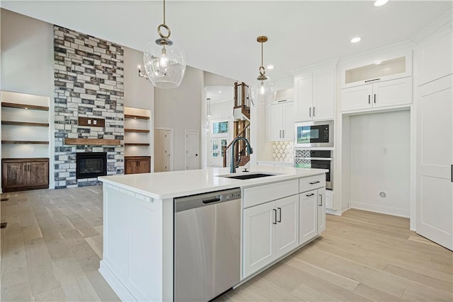 kitchen featuring a kitchen island with sink, decorative light fixtures, white cabinets, and appliances with stainless steel finishes