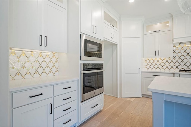 kitchen with black microwave, white cabinetry, oven, and decorative backsplash