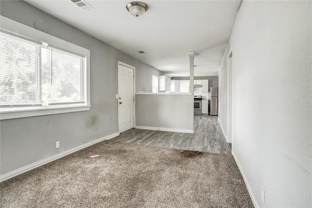 unfurnished living room with carpet flooring and a wealth of natural light