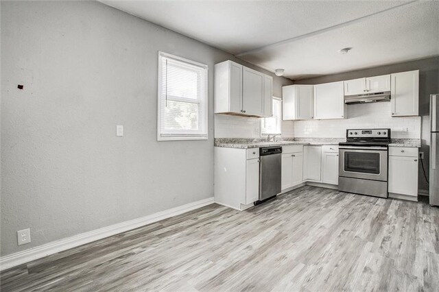 kitchen featuring light hardwood / wood-style floors, appliances with stainless steel finishes, decorative backsplash, and white cabinetry