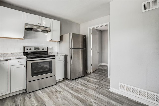 kitchen with appliances with stainless steel finishes, light hardwood / wood-style flooring, decorative backsplash, and white cabinets