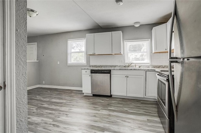 kitchen featuring light wood-type flooring, stainless steel appliances, tasteful backsplash, and white cabinetry