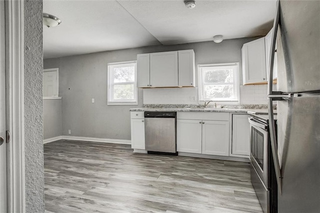 kitchen featuring white cabinetry, sink, decorative backsplash, stainless steel appliances, and light wood-type flooring