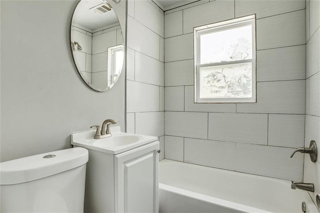 full bathroom featuring vanity, tiled shower / bath, and toilet