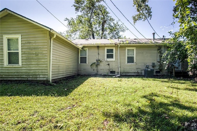 rear view of house with central AC unit and a lawn