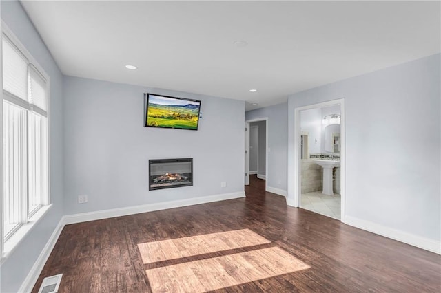 22750 Switzer Rd, Bucyrus, KS 66013 - unfurnished living room featuring wood finished floors, a glass covered fireplace, visible vents, and baseboards