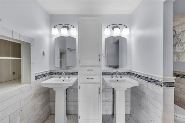 22750 Switzer Rd, Bucyrus, KS 66013 - full bathroom with two sinks, wainscoting, tile walls, and tile patterned floors