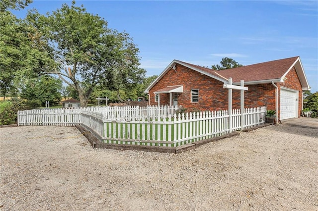 22750 Switzer Rd, Bucyrus, KS 66013 - view of side of home with a fenced front yard, brick siding, and an attached garage