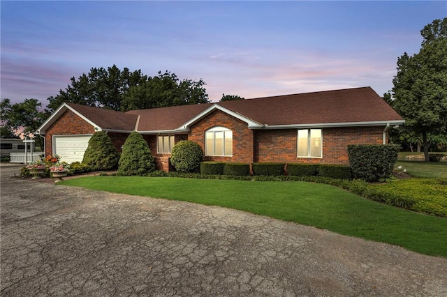22750 Switzer Rd, Bucyrus, KS 66013 - ranch-style home with a garage, driveway, a front lawn, and brick siding