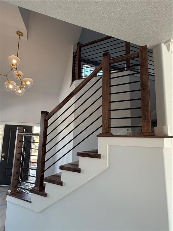 stairs featuring a textured ceiling and an inviting chandelier