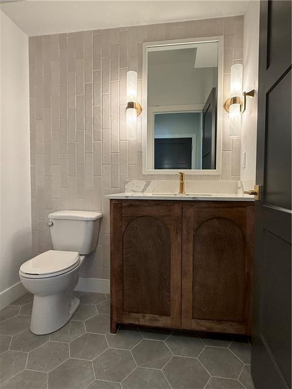 bathroom featuring vanity, tile walls, tile patterned floors, and toilet