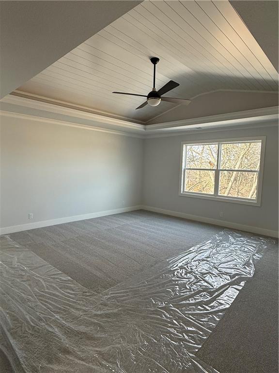 carpeted spare room with ornamental molding, wooden ceiling, a raised ceiling, and baseboards