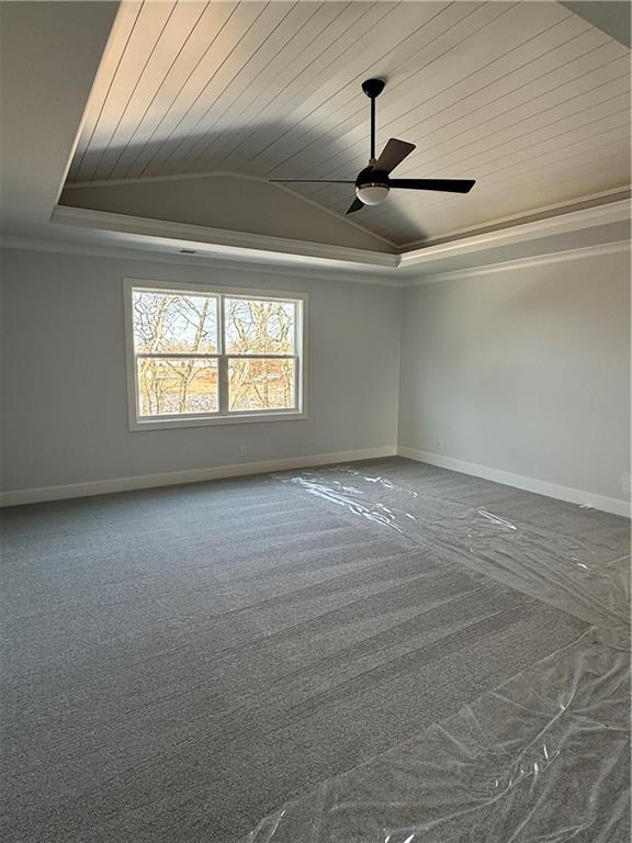 empty room featuring lofted ceiling, carpet floors, ornamental molding, wood ceiling, and a tray ceiling