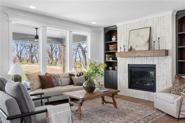 18452 Windsor St, Overland Park, KS 66085 - living area featuring built in shelves, wood finished floors, ceiling fan, a fireplace, and ornamental molding