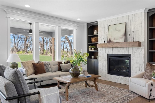 18452 Windsor St, Overland Park, KS 66085 - living room featuring built in features, a ceiling fan, wood finished floors, a fireplace, and ornamental molding