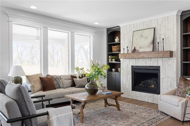 18452 Windsor St, Overland Park, KS 66085 - living area featuring built in shelves, wood finished floors, ceiling fan, crown molding, and a fireplace