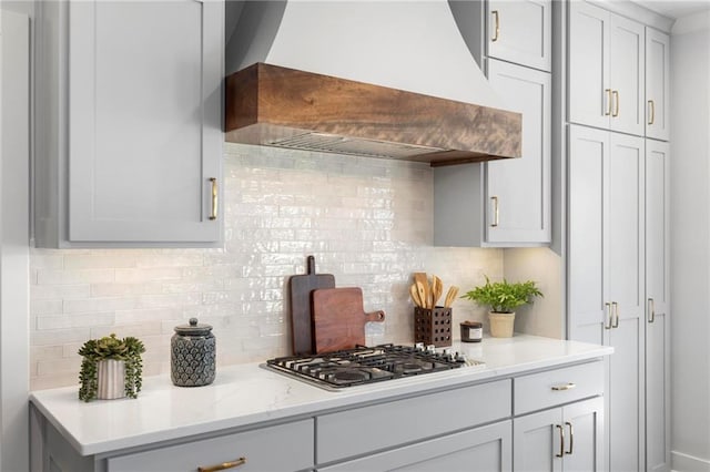 18452 Windsor St, Overland Park, KS 66085 - kitchen featuring stainless steel gas cooktop, custom exhaust hood, tasteful backsplash, and light stone countertops