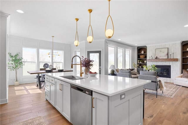 18452 Windsor St, Overland Park, KS 66085 - kitchen featuring light countertops, stainless steel dishwasher, a sink, a fireplace, and built in shelves
